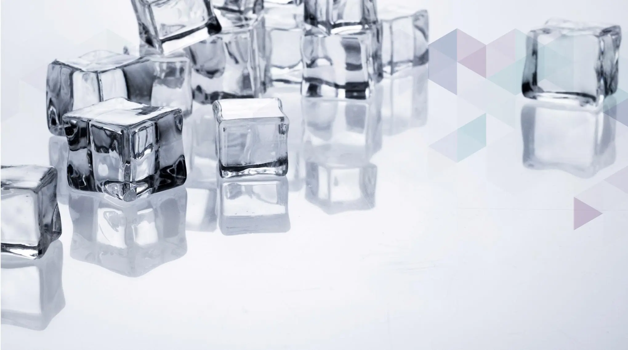 Mehrere transparente Eiswürfel liegen auf einer reflektierenden weißen Oberfläche Mehrere transparente Eiswürfel liegen auf einer reflektierenden weißen Oberfläche