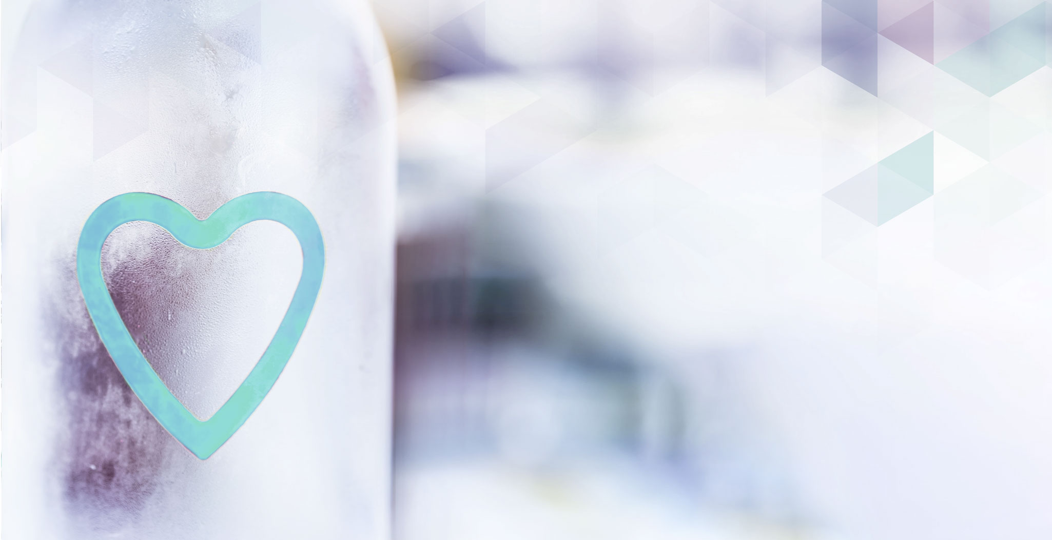 Glasflasche mit einem Herzsymbol auf der Vorderseite vor unscharfem, hellen Hintergrund